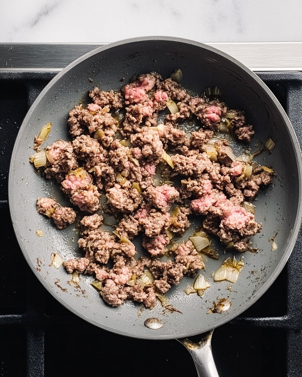 A white pan filled with cooked ground meat mixed with cooked spinach leaves. The meat is brownish with a reddish tint from sauce or seasoning, and the spinach is dark green and wilted, spread evenly throughout the meat. The pan sits on a stove with black grates, and the background shows a white marbled surface. The dish looks saucy with some oil spots around the edges of the pan. photo taken with an iphone --ar 4:5 --v 7