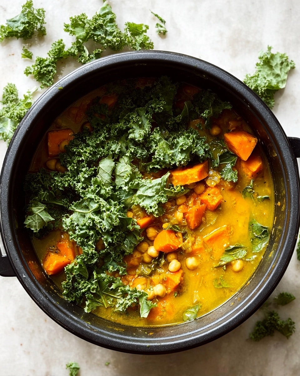 A close-up of a gray bowl filled with a soup that has four main layers: large soft orange-yellow chunks of pumpkin, bright green kale leaves, light beige chickpeas, and a pale yellow broth with sesame seeds sprinkled all over. A silver spoon holds a piece of pumpkin, some chickpeas, and kale near the center. In the background, there's a wooden dish with sesame seeds and some small yellow cubes, all placed on a white marbled surface. photo taken with an iphone --ar 4:5 --v 7