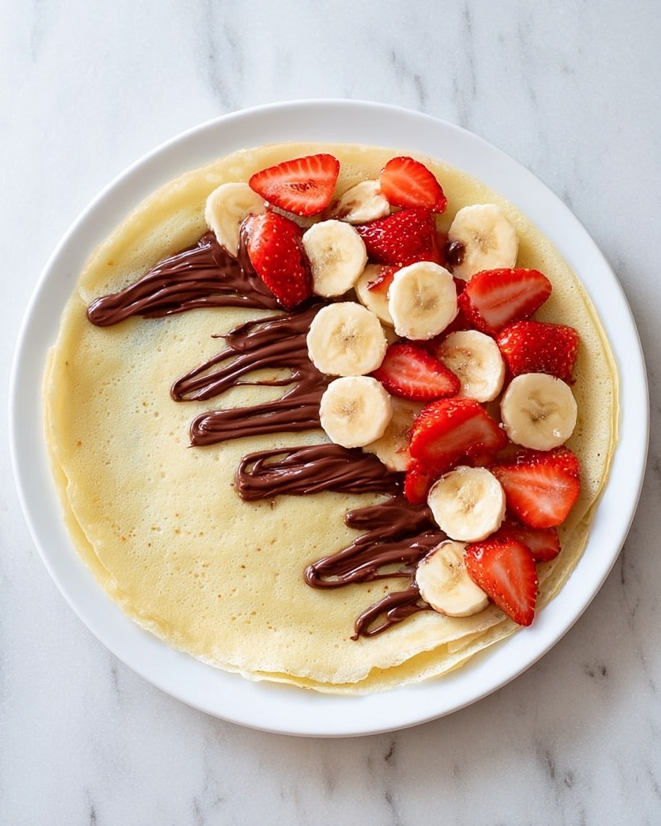 A white plate holds a stack of three thin crepes, each folded in half and layered with slices of red strawberries and light yellow banana. Between the crepes, there are lines of dark brown chocolate spread, visible around the edges. The crepes are dusted lightly with white powdered sugar. On top, bright red strawberry slices and banana pieces decorate the final crepe. The background shows a white marbled texture surface with a blurred strawberry in the back corner. photo taken with an iphone --ar 4:5 --v 7